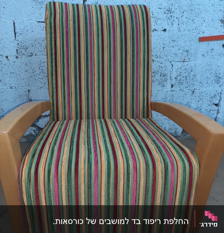 כיסא מרופד בפסים צבעוניים על רקע קיר בטון